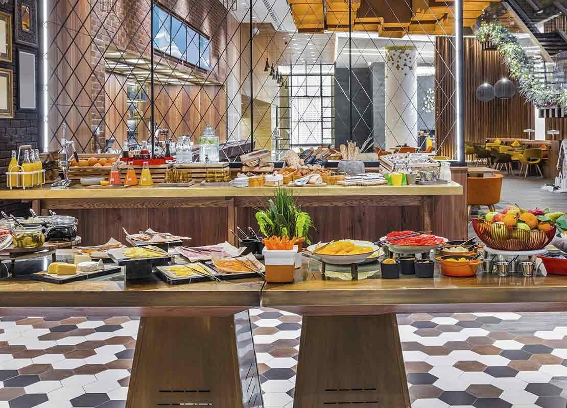 Desayuno tipo buffet con mesas de vegetales, proteínas, frutas, bebidas, entre otras preparaciones