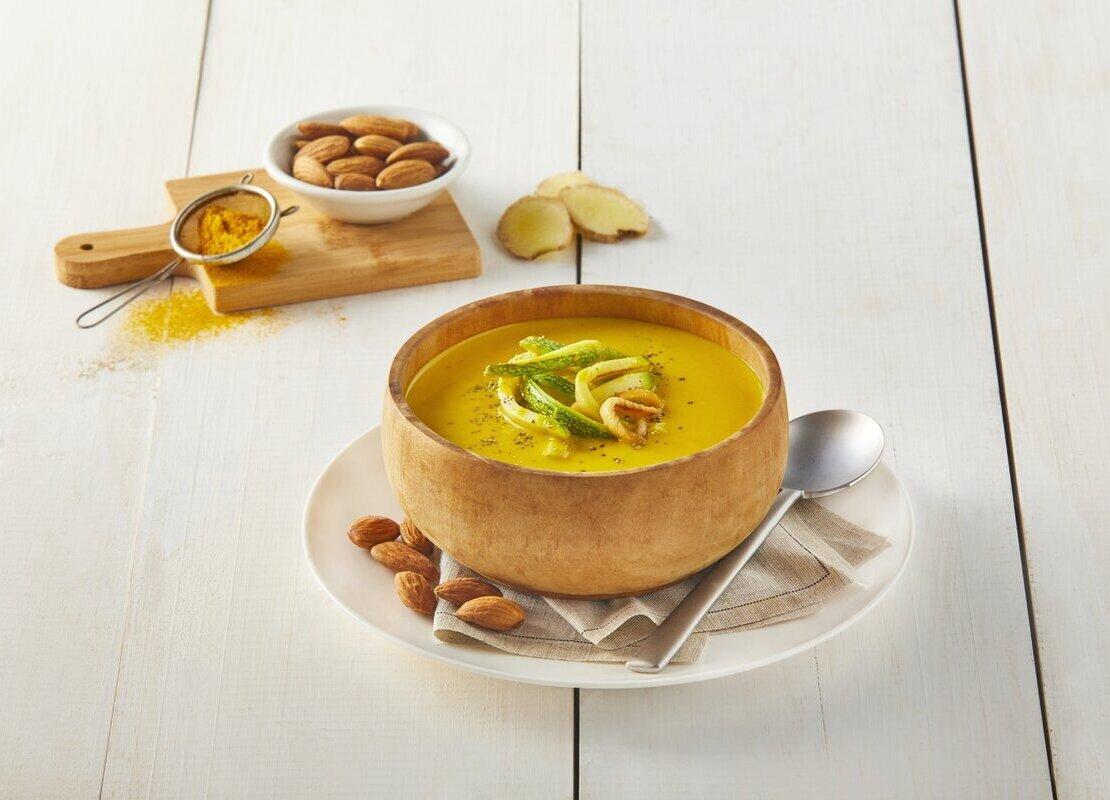 Crema de calabaza, almendra y curry, al lado una tabla de cortar con los ingredientes veganos