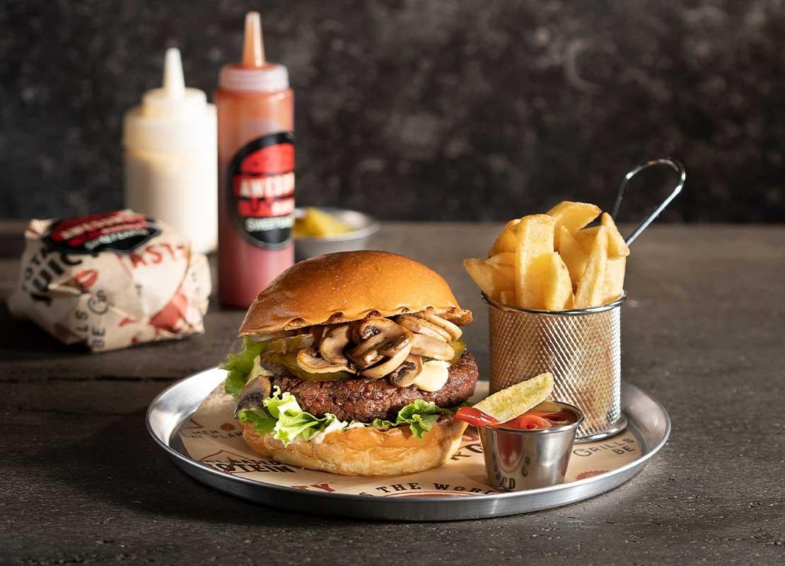 Hamburguesa elaborada con ingredientes de origen vegetal, papas y salsa sobre una bandeja
