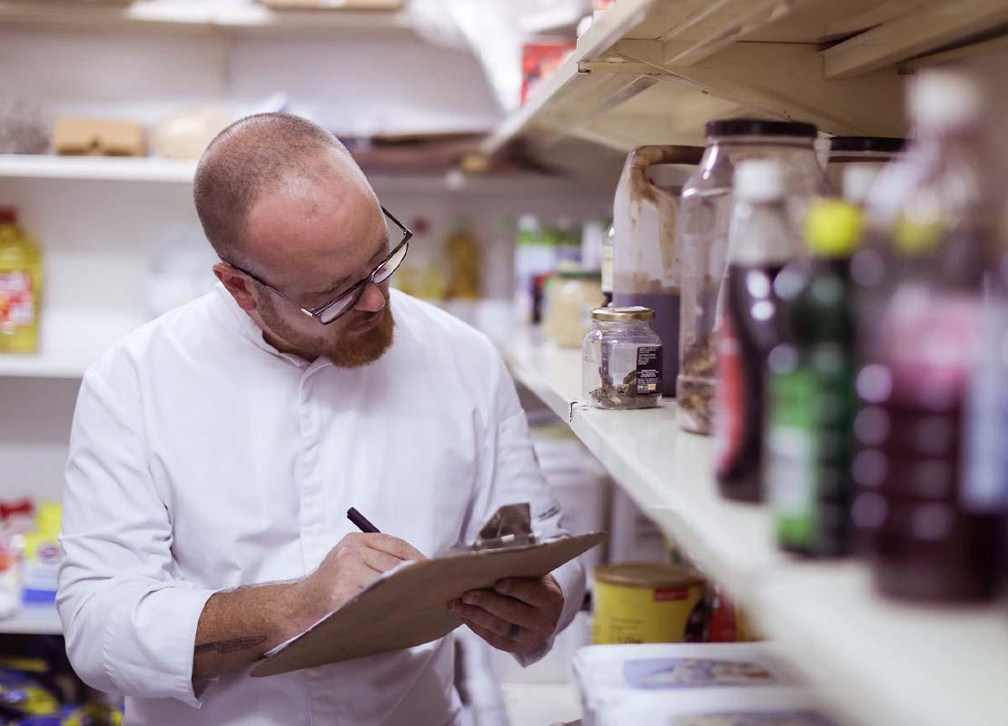 Chef ejecutivo en el almacén de un restaurante revisa y hace inventario de los ingredientes e insumos