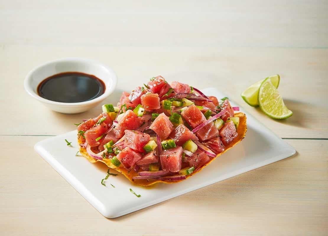 Platillo con ceviche sobre una “lámina” de plátano, al lado rebanadas de limón y salsa de soya