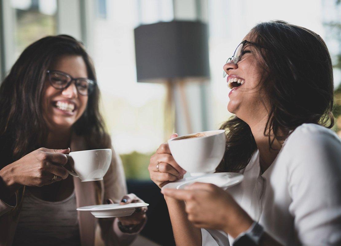 Dos jóvenes beben café y conversan, reflejando distintos tipos de consumidores en cafeterías.