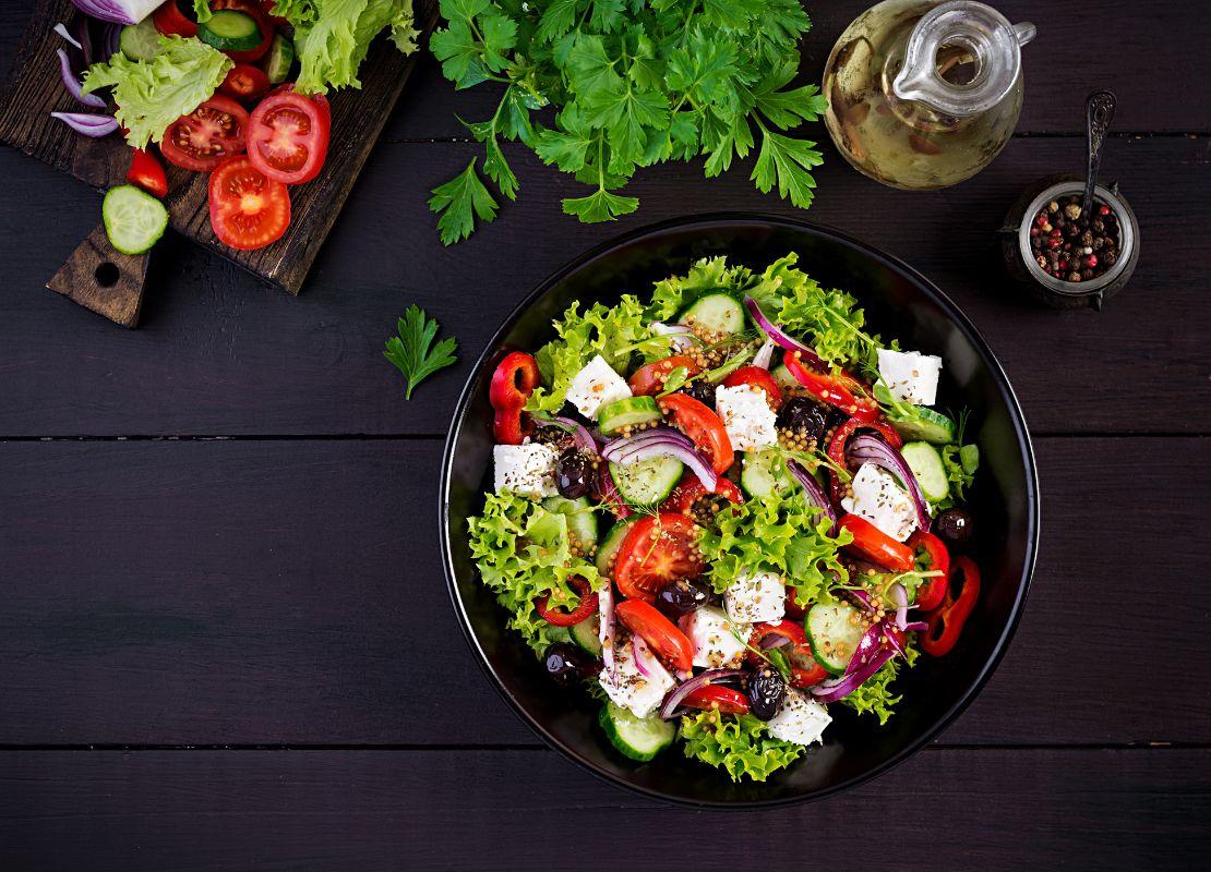 Ensalada con lechuga, tomate, pepino, queso y aceitunas en bowl