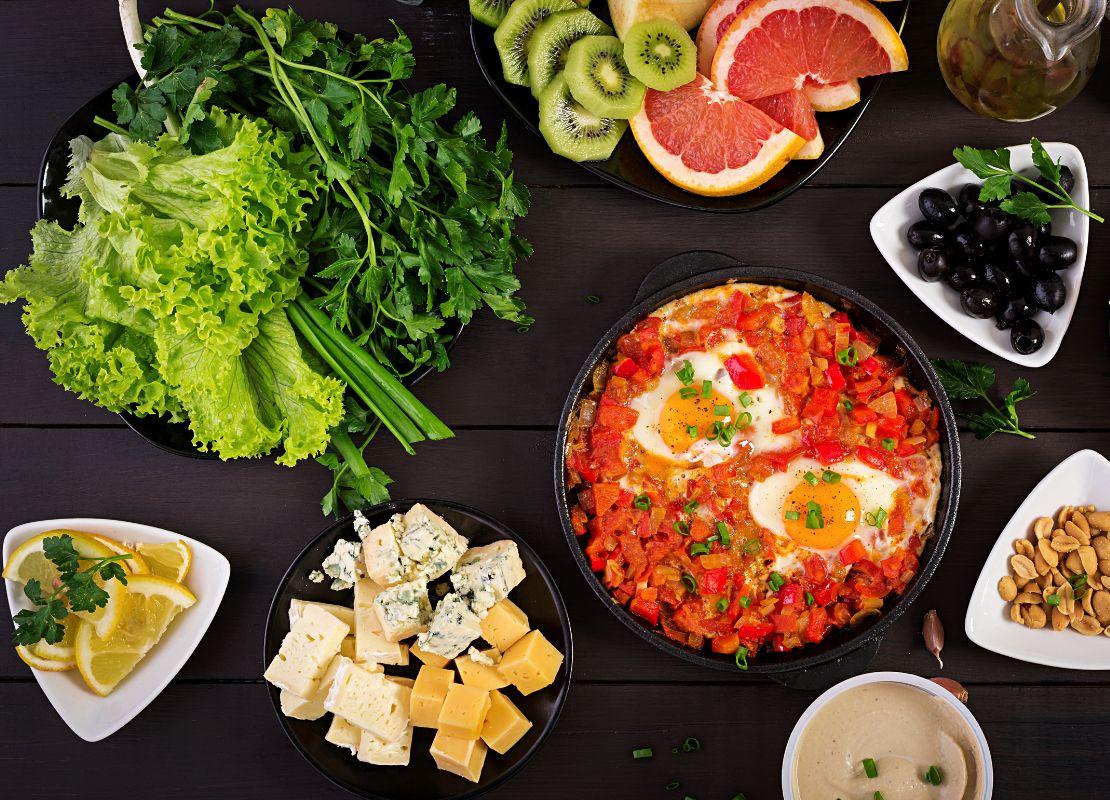 Plato con huevos en salsa roja acompañado de queso, pan y vegetales