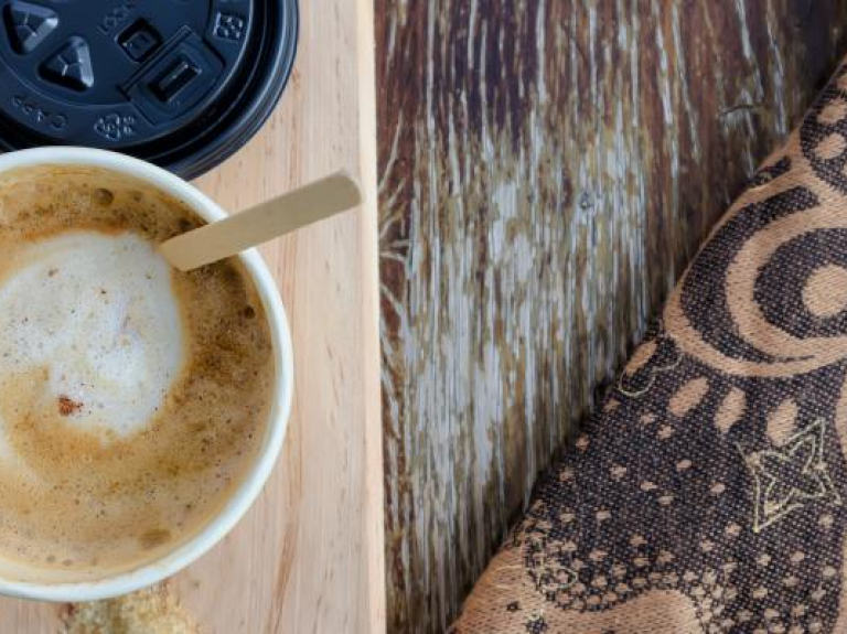 Una taza de cappuccino espumoso en plano cenital sobre una mesa de madera