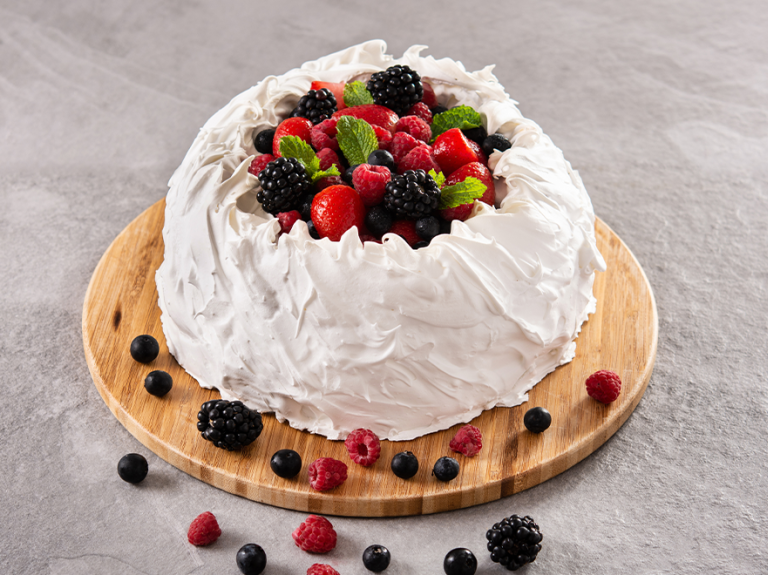 Pavlova con merengue y frutas del bosque sobre base redonda de madera