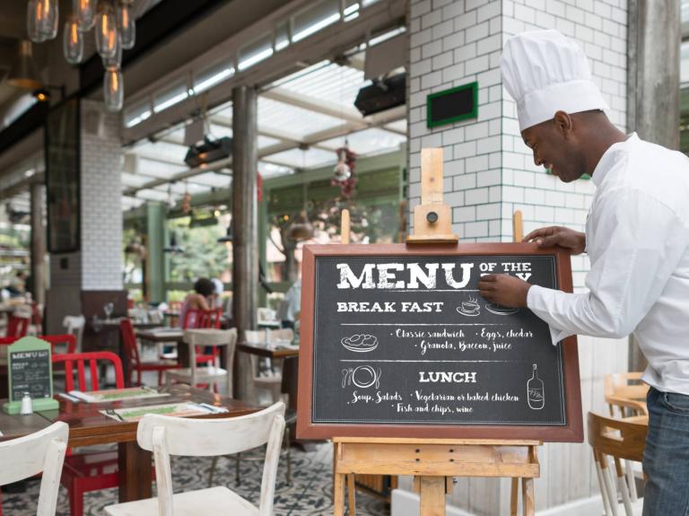 Chef poniendo un menú en la entrada para fidelizar clientes