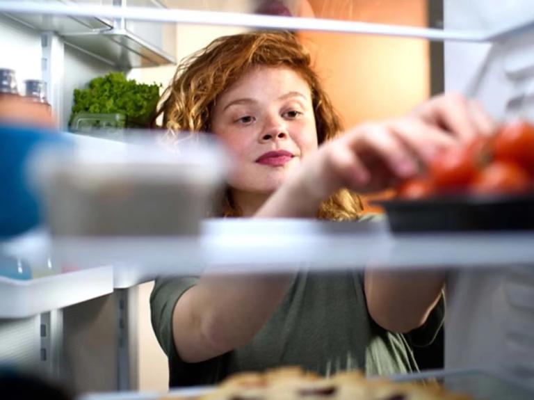 Mujer almacena tomates en el refrigerador junto a otros alimentos