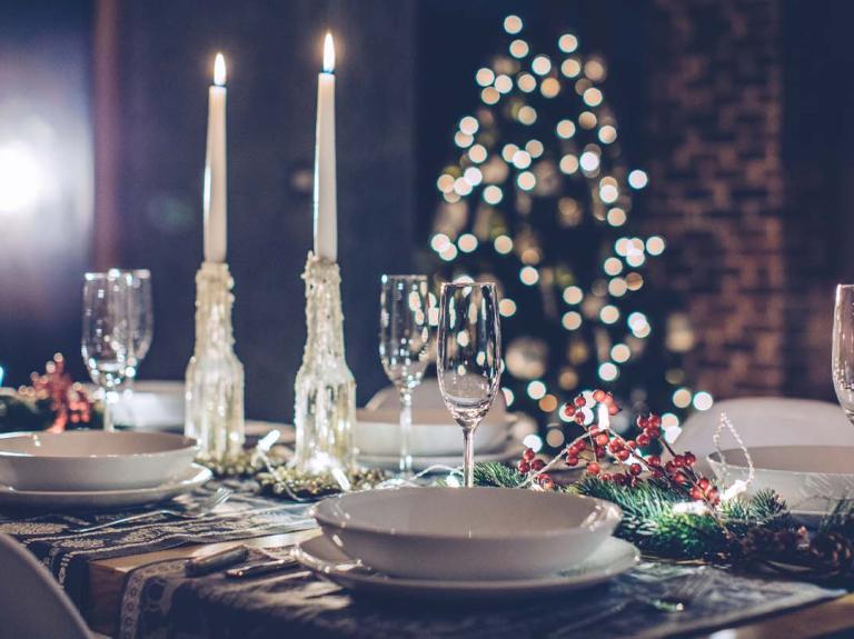 Cena para Navidad con copas de vino, velas y árbol