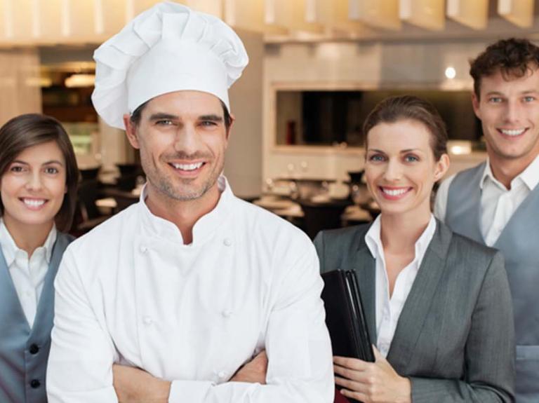 Dos camareros, una gerente de restaurante y un chef que recibieron capacitación de personal para tener un equipo eficiente