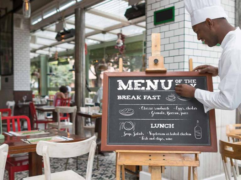 Chef escribe un menú de restaurante a las afueras de su negocio