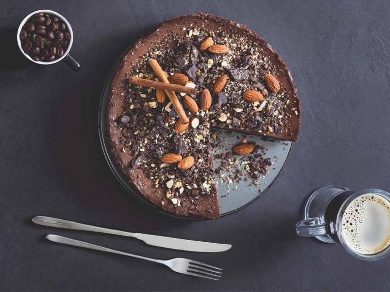 Vista superior de tarta de mousse de chocolate con almendras y café sobre fondo de pizarra que hacen un maridaje perfecto