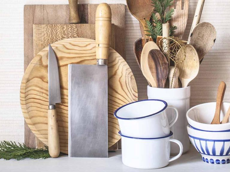 Utensilios de cocina en madera como diversas tablas de picar, cuchillos, cucharas, mezcladores, espátulas, tazas y pocillos