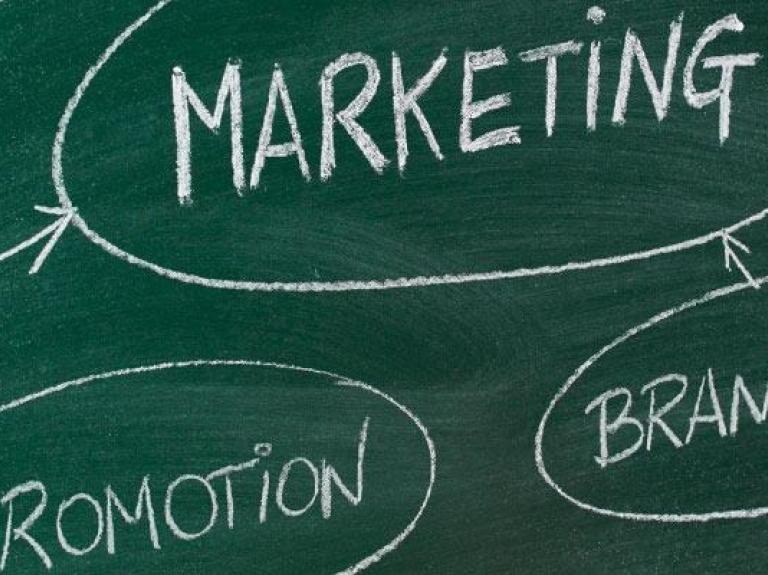 Pizarra verde con las palabras "Marketing, Promoción y Branding" escritas en ella