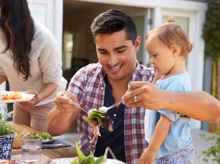 Papá come con su hija y familia al aire libre para celebrar el Día del Padre