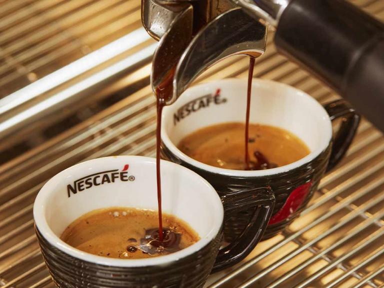 Filtro de una máquina vierte a presión café sobre dos tazas de NESCAFÉ®