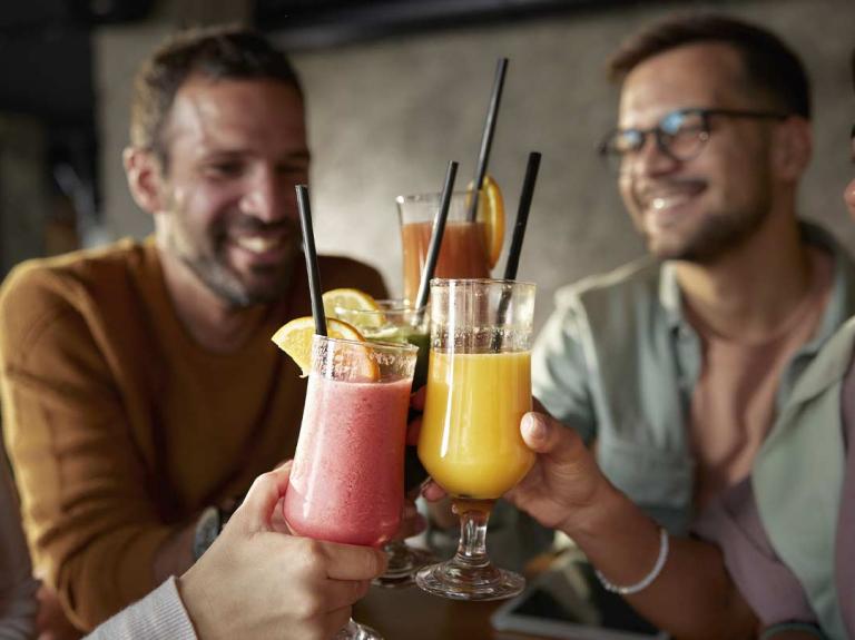 4 amigos felices brindan con mocktails de frutas en un negocio de food service