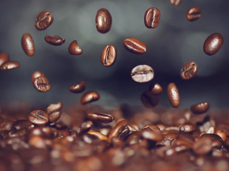 Sobre una pila de granos de café tostado, otros van cayendo