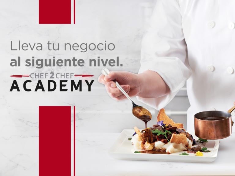 Una persona con bata blanca de Chef 2 Chef Academy, prepara un plato con ingredientes frescos y técnicas profesionales