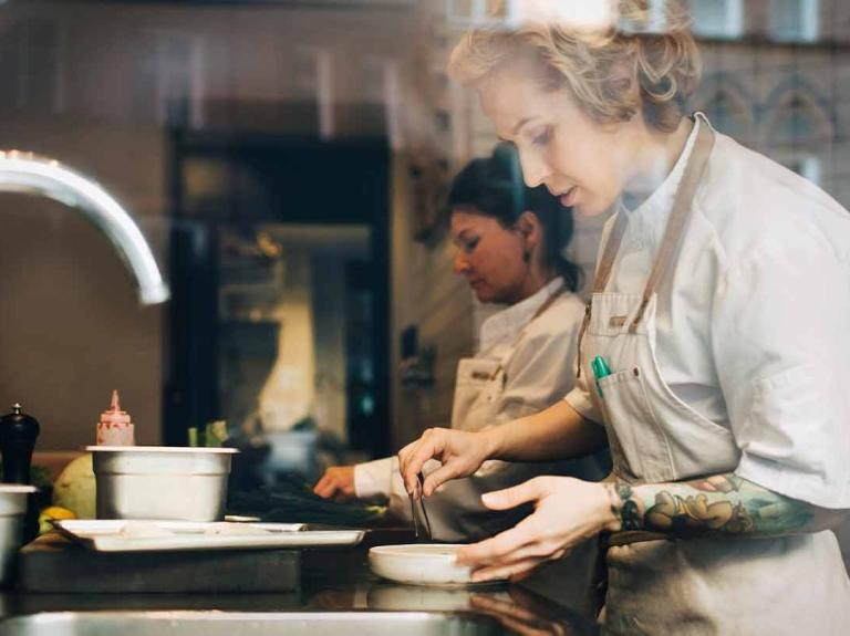 Dos chefs lavan y seleccionan ingredientes en el mesón de una cocina comercial