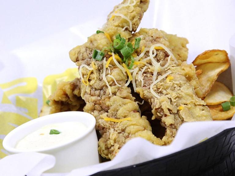 Un canasto con tiras de pollo empanizadas y salsa dip, ideal para un menú fácil y rápido.