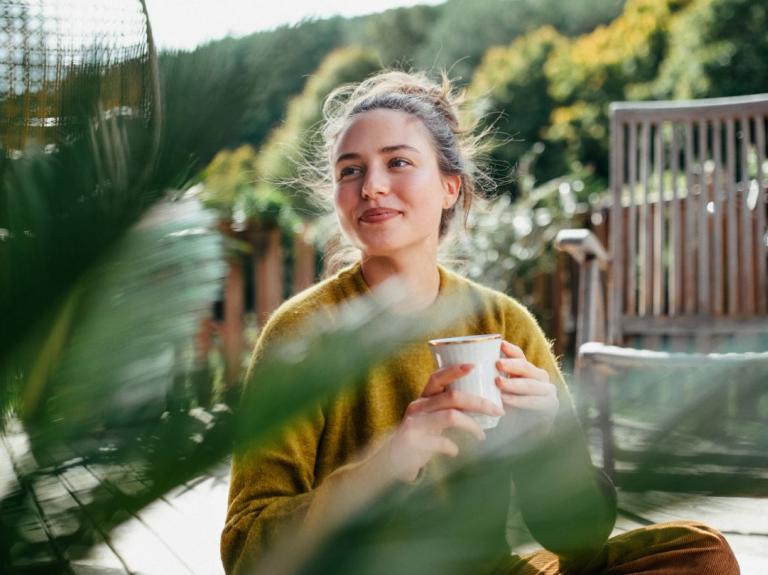 Persona disfrutando una degustación de café en un espacio al aire libre de un negocio gastronómico.