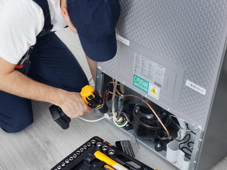 Técnico realiza mantenimiento de equipos de cocina en un sistema de refrigeración profesional.