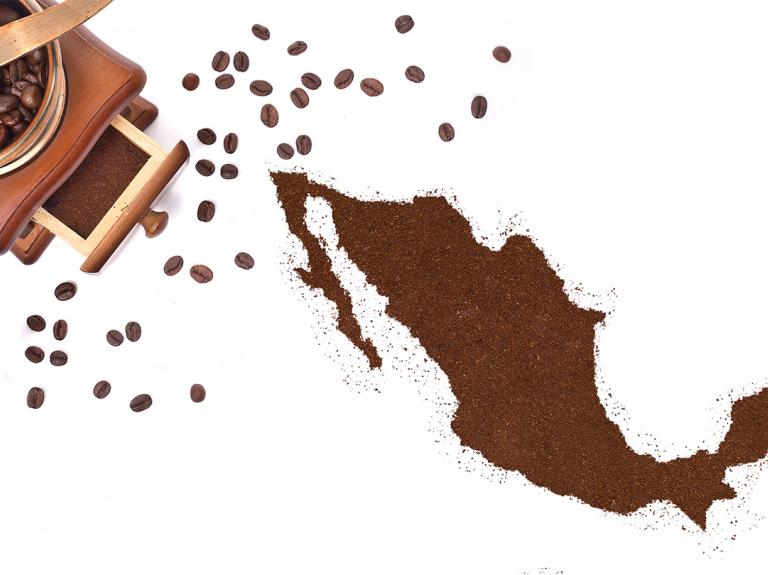 Mapa de México formado con café molido junto a molino y granos tostados dispersos