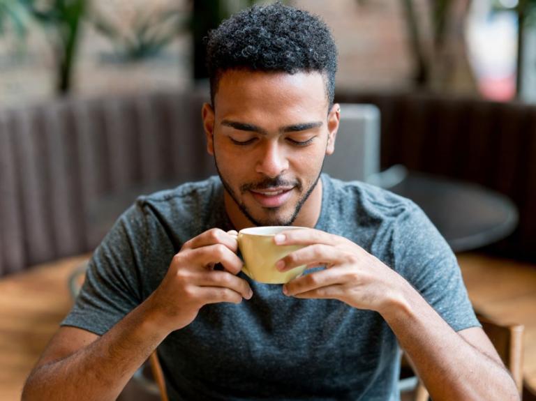 Cliente disfruta una taza caliente explorando sabores de café en un entorno de cafetería.
