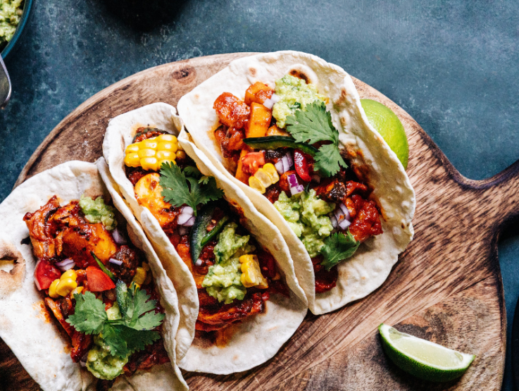 Tres tacos de carne sobre base de madera