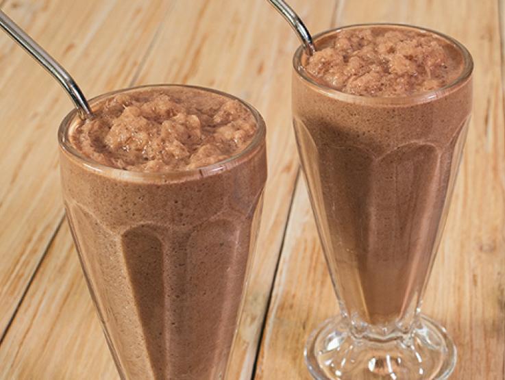 Dos vasos de malteadas preparadas con NESQUIK® sobre una mesa de madera