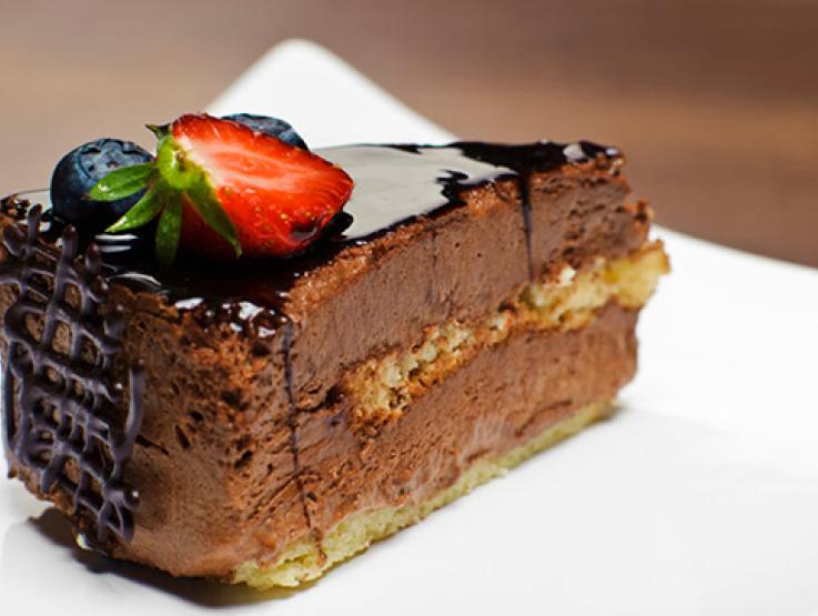 Trozo de pastel elaborado con productos CRUNCH® cubierto con salsa de chocolate y decorado con fruta