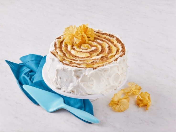 Un pastel en espiral con glaseado de tu proveedor de lácteos al por mayor, sobre un soporte con una servilleta azul.