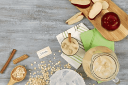Jarra y vaso con bebida de avena y canela junto a una manzana entera y en trozos y un sobre de Splenda
