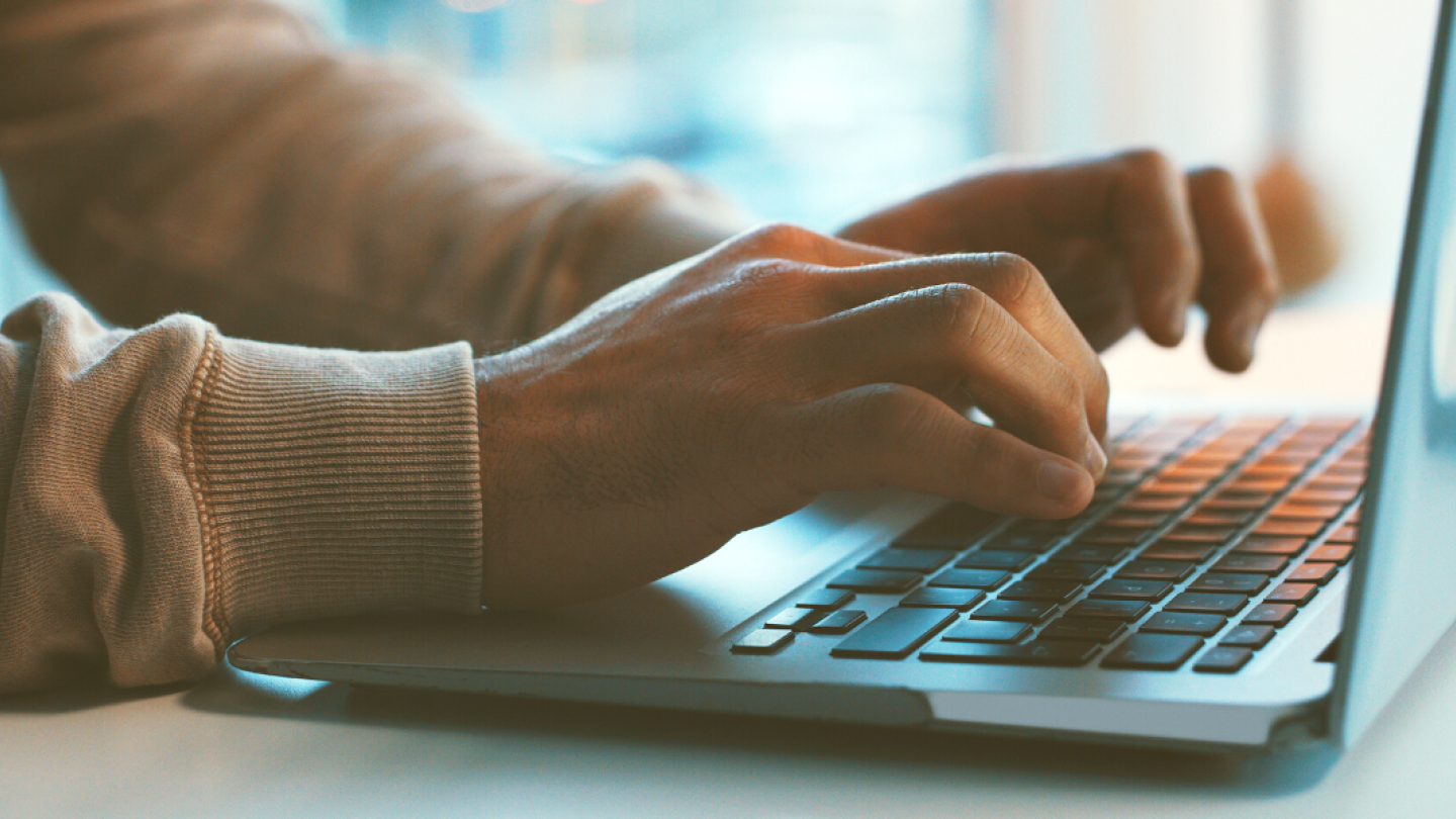 Manos de hombre escribiendo en una computadora portátil 