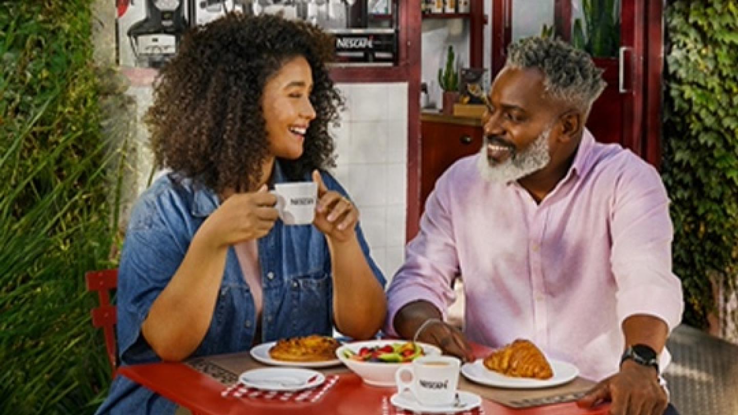 Una pareja feliz comparte un brunch con NESCAFÉ® en una cafetería