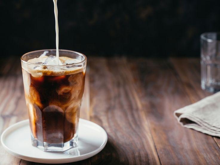 Vaso de café frío con hielo y bebida vegetal servido sobre una mesa de madera