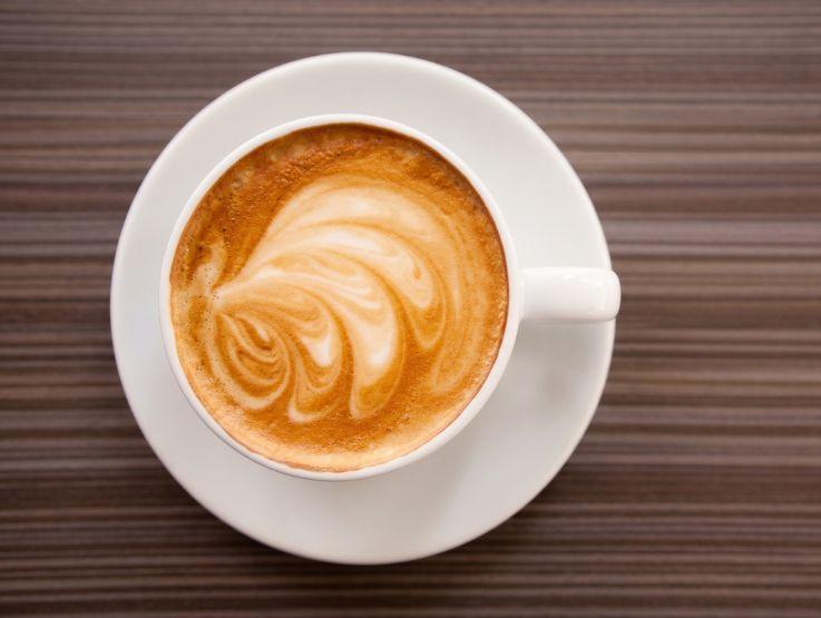 Taza de cappuccino con espuma y diseño en la superficie con art latte