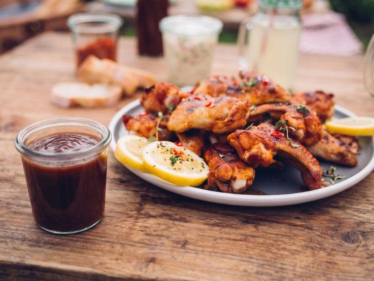 Alitas de pollo bañadas en salsa espesa tipo BBQ con brillo, presentadas en plato metálico