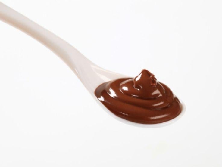 Cucharada de crema de chocolate espesa y suave servida sobre un fondo completamente blanco