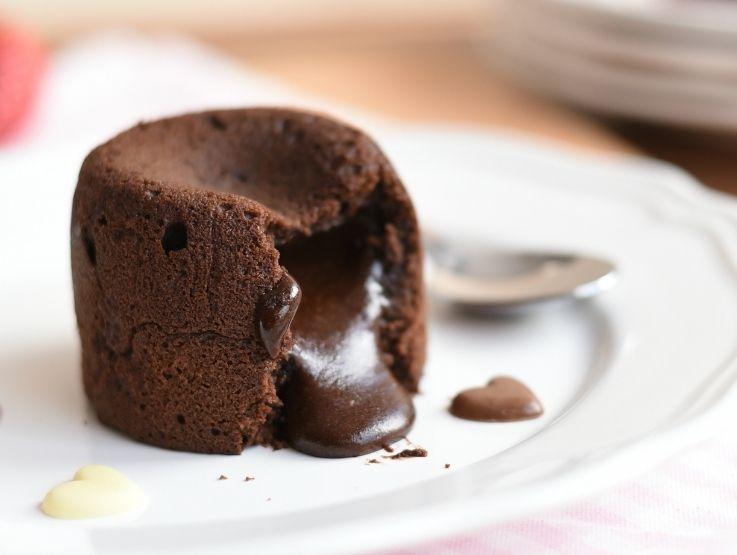 Volcán de chocolate tibio con centro líquido derretido servido en un plato blanco de porcelana.